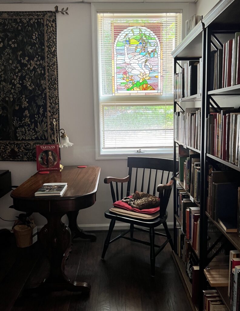 A room with a chair, a table and books on shelves.